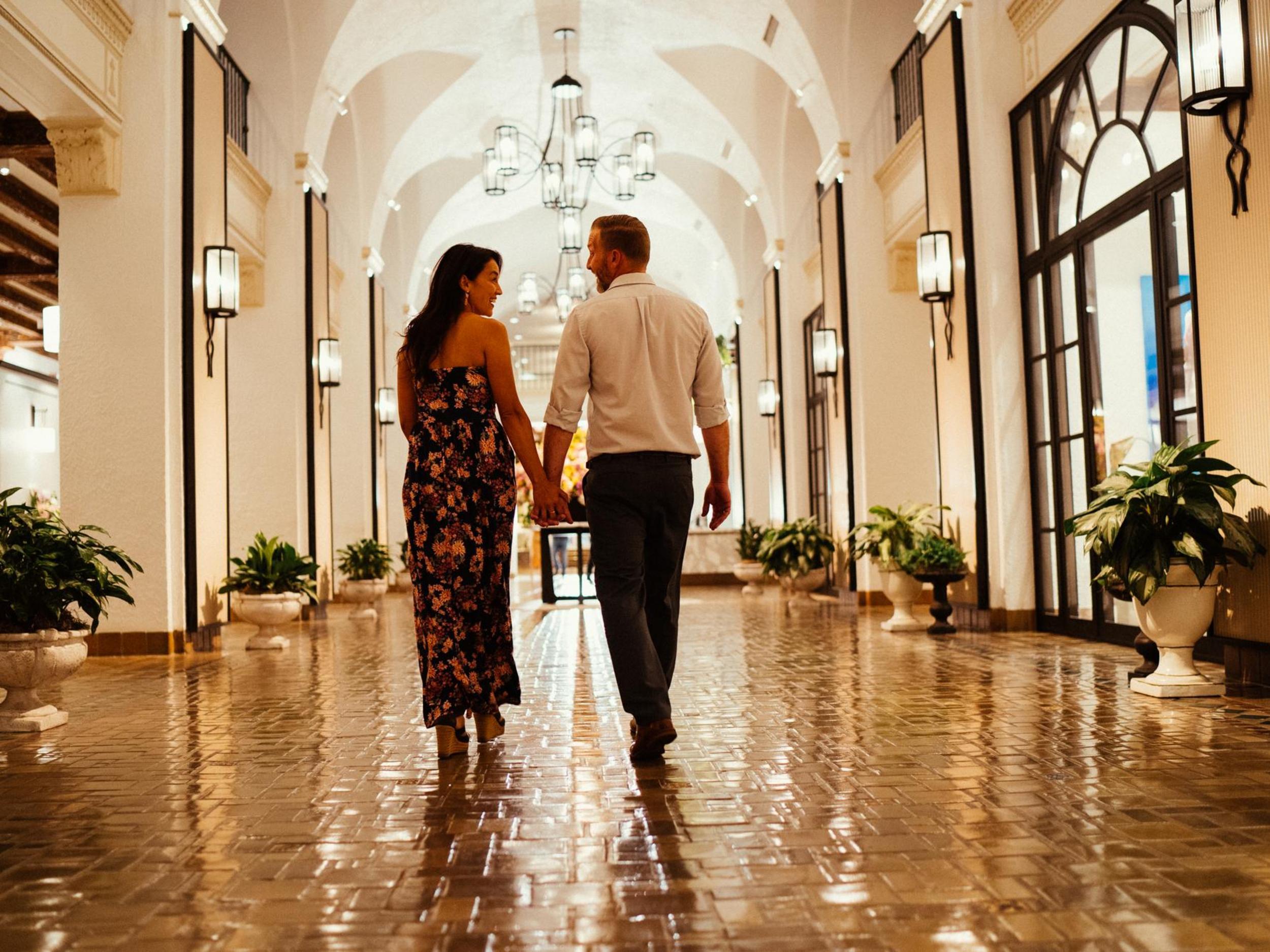 a woman and a man walk down a shiny tiled hallway with arched ceilings at the Vinoy Resort & Golf Club