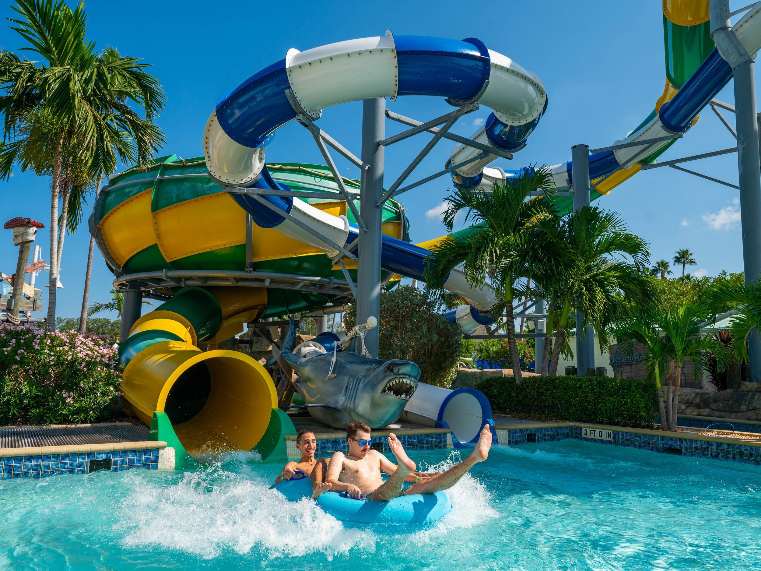 two people in inner tubes splash down into a pool from a twisty water slide at Splash Harbour Water Park