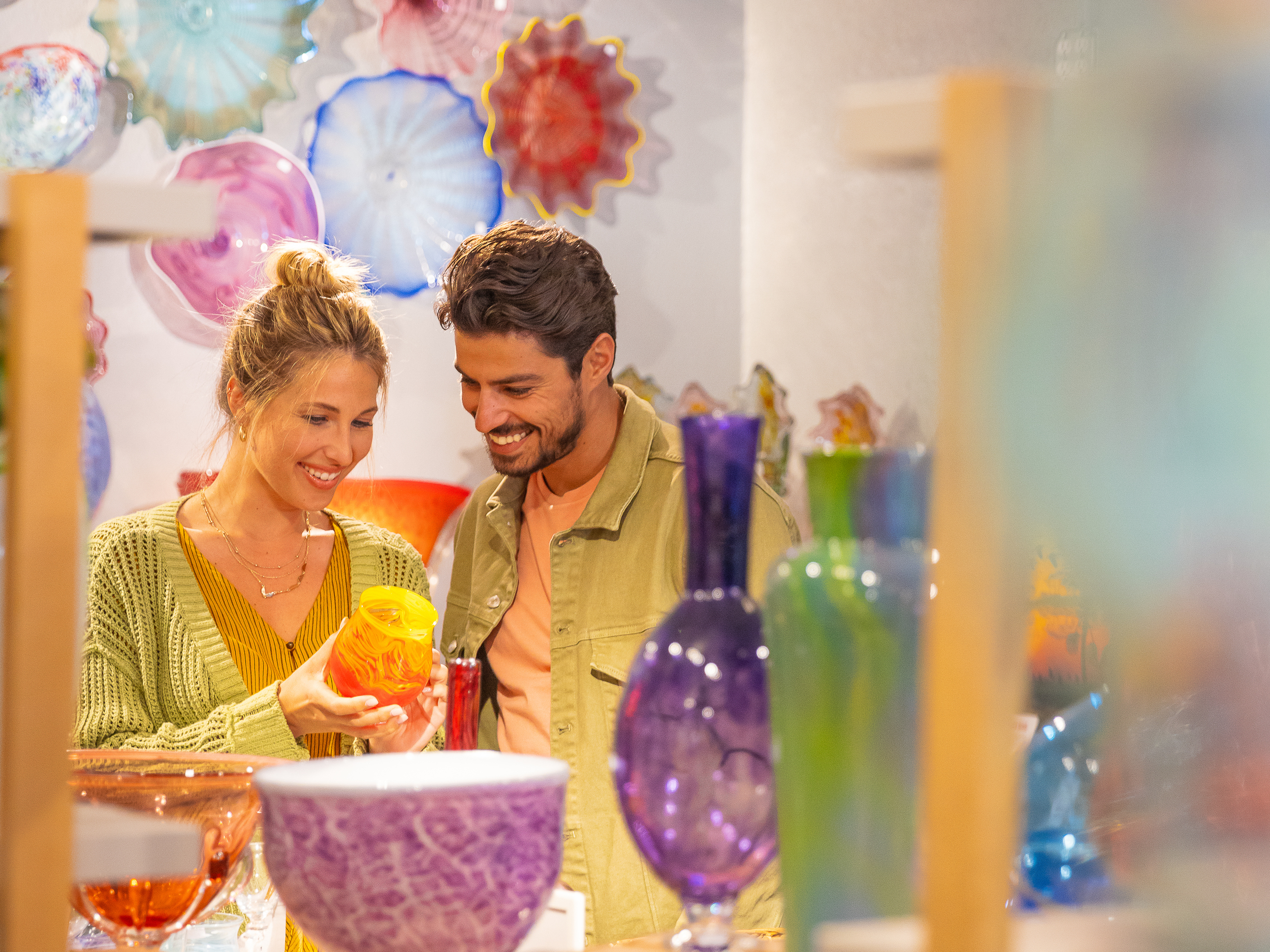 a couple looks at colorful glass art at the Morean Glass Studio