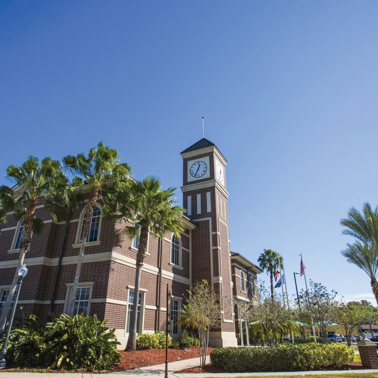 Pinellas Park train station exterior brick walls showing the clock at the top of the tower, blue skies and palm trees.