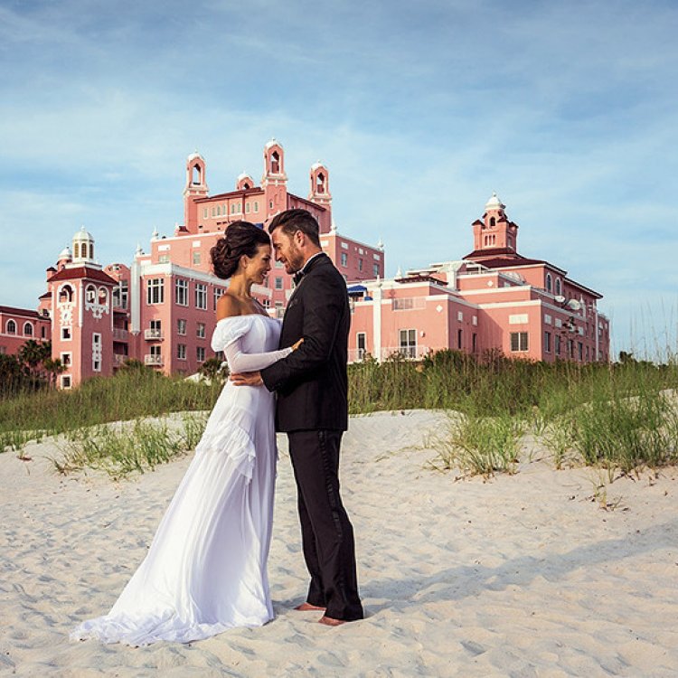 A couple hugging each other posing in front of Don Cesar for their wedding.