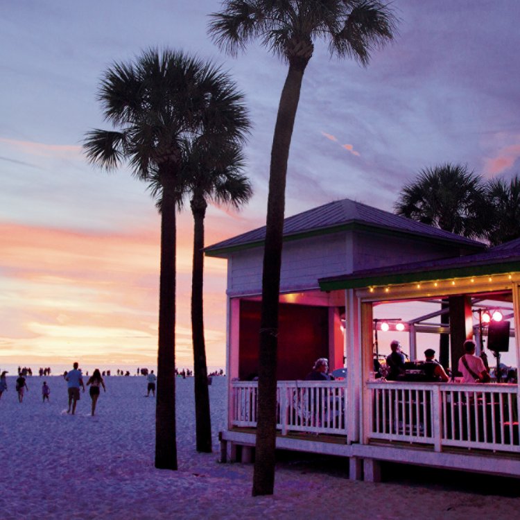 After Sunset view of the beach and Crabby's Beachside Pavilion with palm trees on the beach with a beautiful colorful sky.