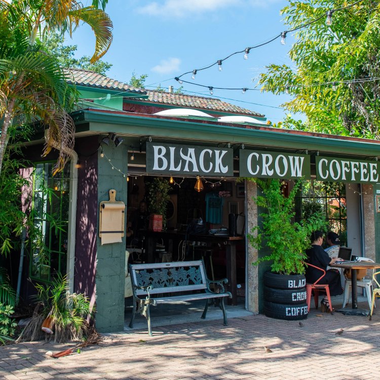 Exterior front view of a garage turned into a coffee bar surrounded by palm trees.  