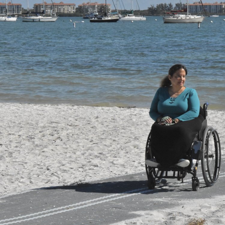 Woman in wheelchair on mat on the beach