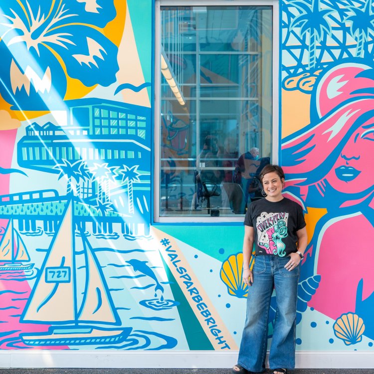 a person in jeans and a black t-shirt stands in front of a pastel colored mural named "be bright" at St. Petersburg Clearwater International Airport