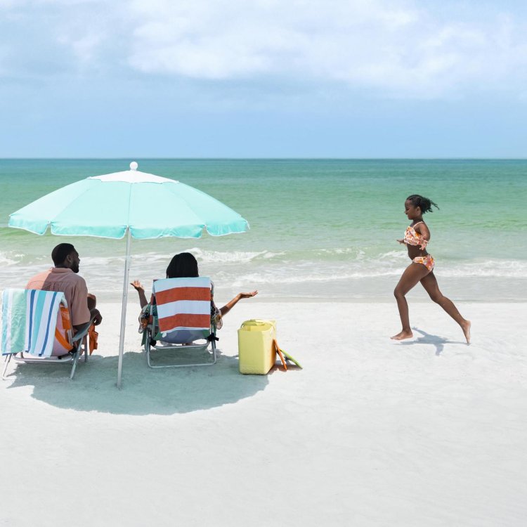 Girl running on the beach toward parents under an umbrella
