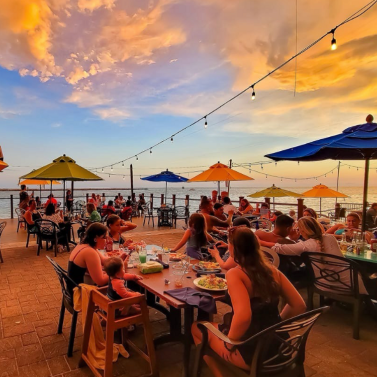 the deck at Jimmy's Fish House & Iguana Bar with people dining at sunset