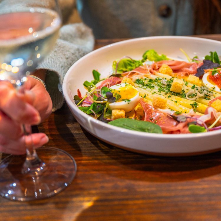 a woman having a salad and a glass of wine at The Restorative in Dunedin
