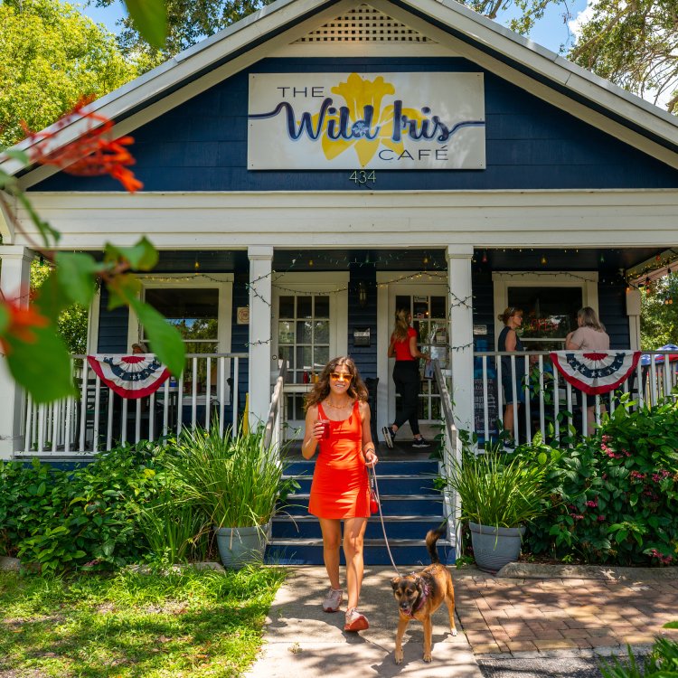 a woman standing with her dog in front of Wild Iris Cafe in Dunedin
