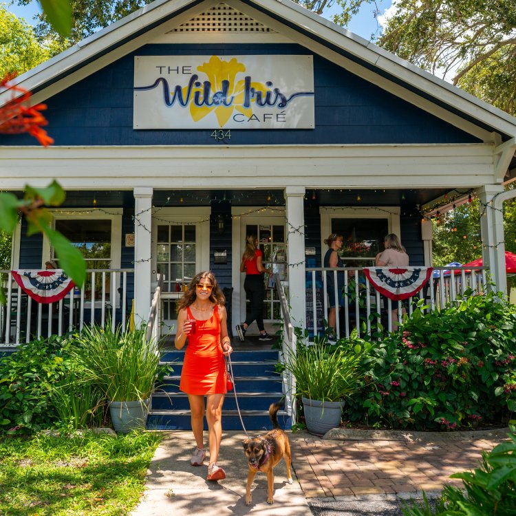 a woman standing with her dog in front of Wild Iris Cafe in Dunedin