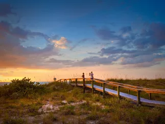 A couple taking photos during sunset at a beach walkway on beautiful Pass-a-Grille Beach near St. Pete Beach, Florida