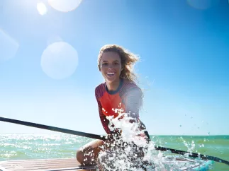 A young woman on a paddleboard splashes water in Anclote Key.