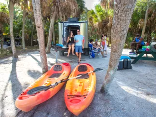 Gente acampando en el parque Fort de Soto con kayaks en primer plano.