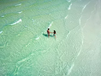 A couple walking in the emerald-green waters of Anclote Key