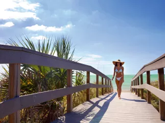 A young woman in white bikini walking off of Indian Rocks Beach.