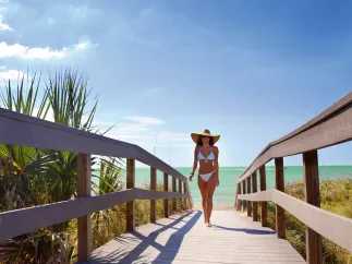 A young lady dressed in bikini walking Indian Rocks Beach boardwalk.