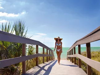 A young lady dressed in bikini walking Indian Rocks Beach boardwalk.