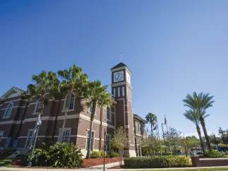 Pinellas Park train station exterior brick walls showing the clock at the top of the tower, blue skies and palm trees.