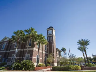 Pinellas Park train station exterior brick walls showing the clock at the top of the tower, blue skies and palm trees.