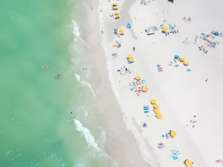 Aerial view of yellow beach cabanas and emerald-green waters of Treasure Island.
