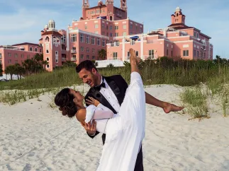 A groom sweeps up his bride in front of the Don CeSar