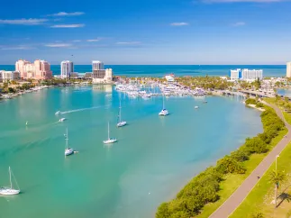 An aerial view of Clearwater Marina and Memorial Causeway showing green waters and bright blue sky.