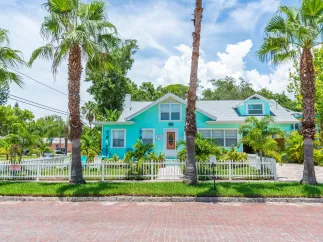 A blue house with palm trees around it seen from the road in Gulfport.
