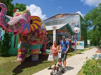 Um casal passeando com uma criança em frente ao elefante rosa em frente ao Safety Harbor Art & Music Center