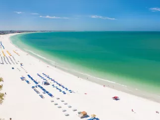 St. Pete Beach aerial panoramic photo showing the entire green waters beach, white sand and lots of hotels cabanas.