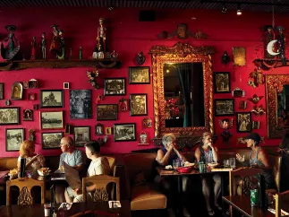 Six dinners eating at Casa Tina restaurant in Dunedin. The wall is red and decorated with multiple portraits.