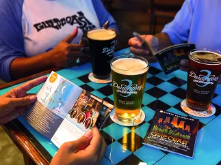 A group of people enjoying beers and reading through the craft beer passport connecting all breweries in Pinellas County.