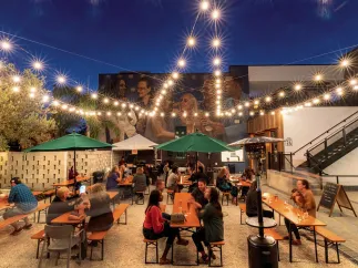 Several people enjoying drinks in the outdoor area of Grand Central Brew House at dusk.