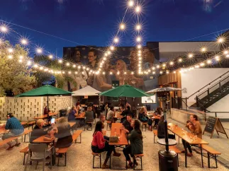 Several people enjoying drinks in the outdoor area of Grand Central Brew House at dusk.