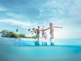Three children play in the ocean in front of an island.