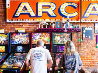 Two people play pin ball at the Replay Museum