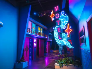 A neon sign outside an artistic replica of a vintage Florida hotel