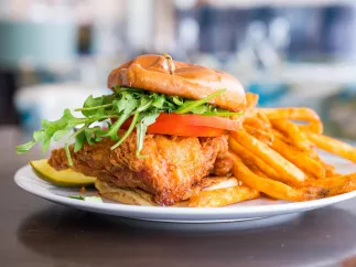 a beer-batter fried grouper sandwich with lettuce and tomatoes and fries on the side