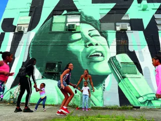 Children and parents playing outside in front of a wall mural in the Deuces Live district during the day.
