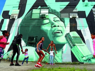 Children and parents playing outside in front of a wall mural in the Deuces Live district during the day.