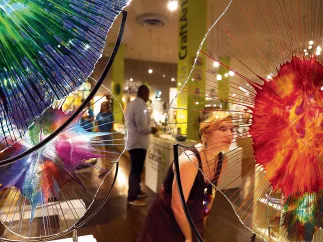 a woman in a black dress peers at a beautiful piece of orange and clear glass art at Florida CraftArt gallery in St. Pete