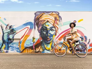 Woman on a bicycle infront of a mural