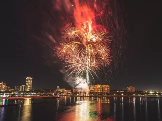 Fogos de artifício vermelhos e brancos explodem sobre o horizonte de St. Pete