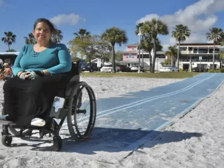 Woman in wheelchair on Mobi Mat on the beach