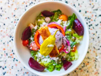 Colorful salad in a white bowl on a speckled table