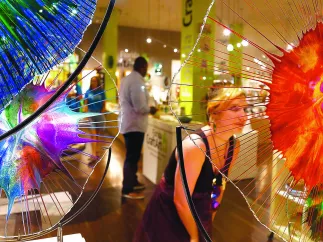 Woman shopping surrounded by colorful glass sculptures.