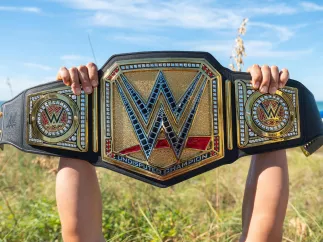 Cropped shot of arms and hands holding the massive WWE belt on the beach