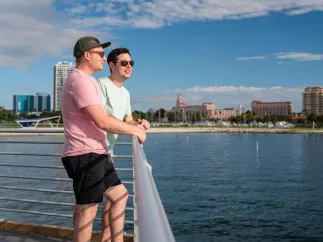 two men stand near a railing looking out over the water near the St. Pete Pier