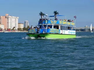 A tropical-themed tour boat cruises through the water during the day.