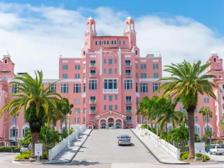 exterior of the historic don cesar hotel which looks like a bright pink castle with palm trees around it