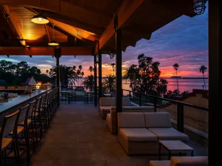 a beautiful rooftop deck and bar at sunset with a view of the water at the Fenway Hotel